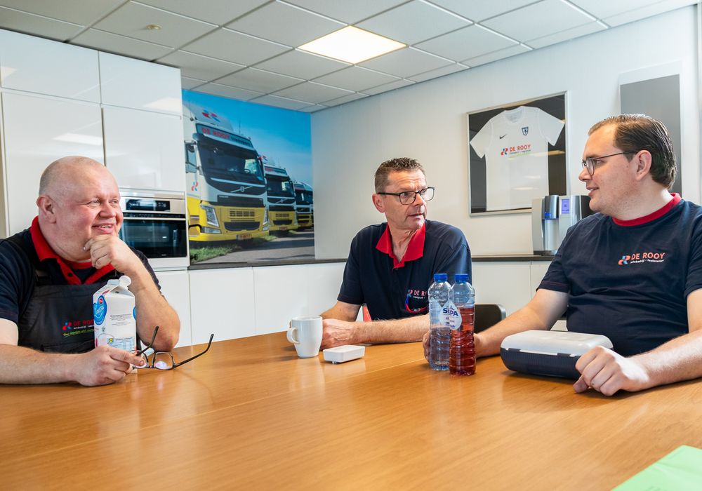 Drie medewerkers van De Rooy Transport in gesprek aan tafel in de kantine