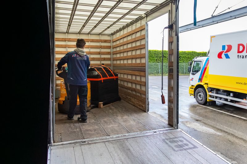 Magazijnmedewerker laadt met een palletwagen een pallet in een bakwagen van De Rooy Transport