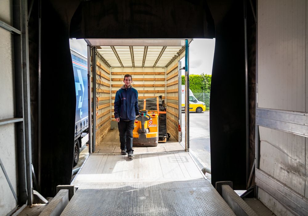 Magazijnmedewerker rijdt met een palletwagen door een trailer aan het laaddock van De Rooy Transport
