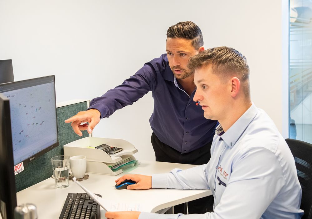 Planner van De Rooy Transport wijst een collega iets aan op het planningsscherm